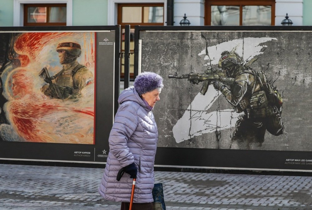 An elderly woman walks past artworks depicting Russian soldiers in Moscow, 5 April 2024. Photo: EPA/YURI KOCHETKOV