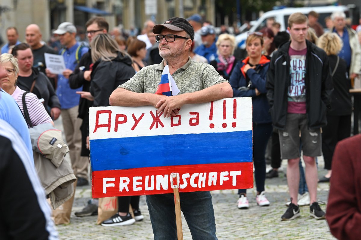 Участник митинга AfD держит плакат в цветах России с надписью «Дружба», 1 июля 2023 года. Фото: Heiko Rebsch / dpa / Picture-Alliance / Scanpix / LETA
